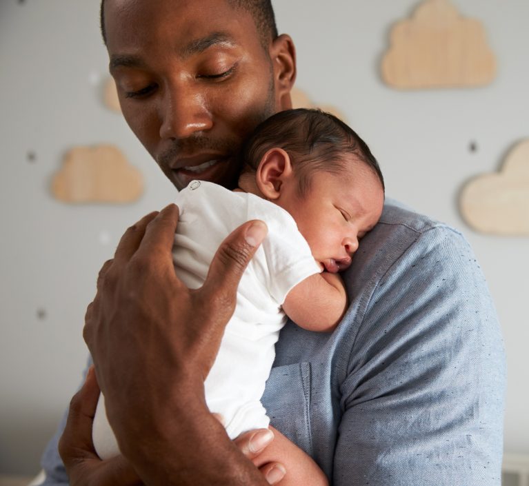 dad holding sleeping baby in a onesie